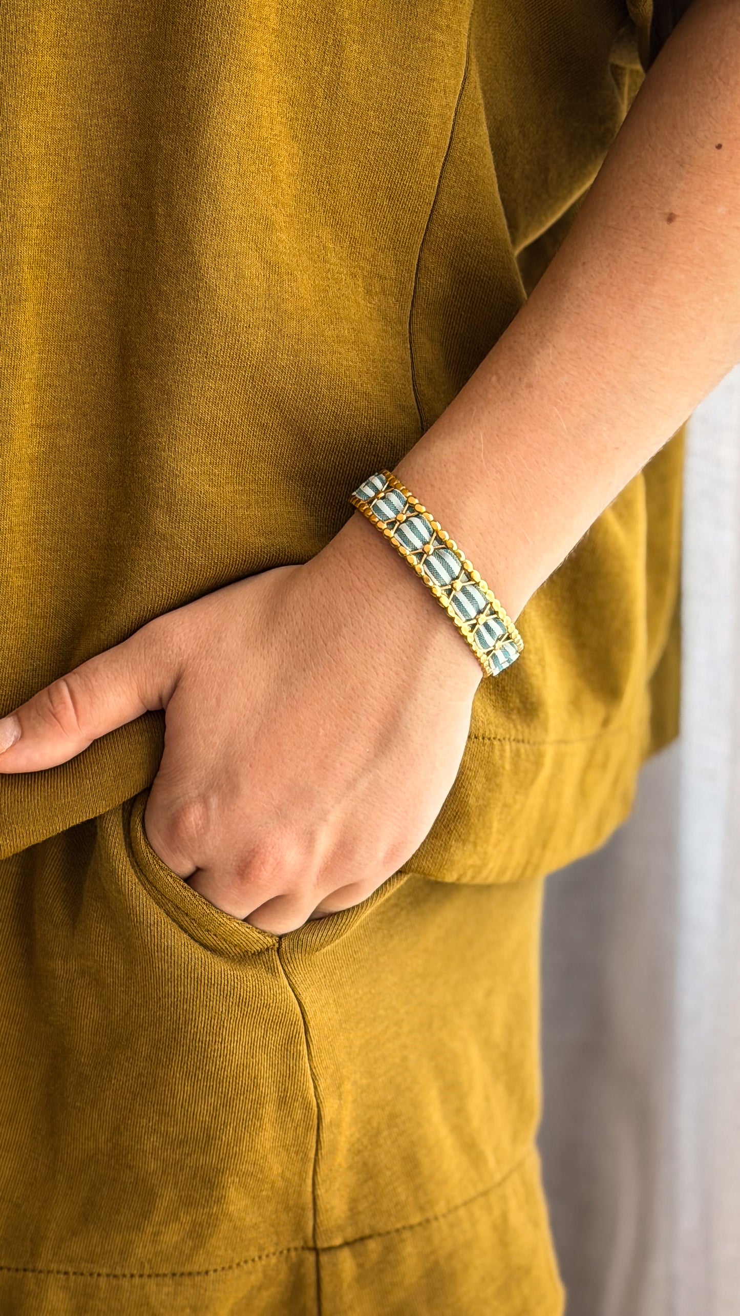 Bracelet jonc en acier inoxydable et tissu upcyclé motif rayé vert sauge, porté au poignet