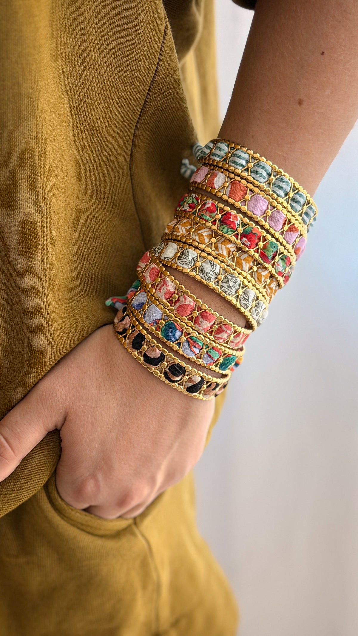 Bracelet jonc en acier inoxydable et tissu upcyclé doré porté empilé avec d'autres bracelets sur le poignet