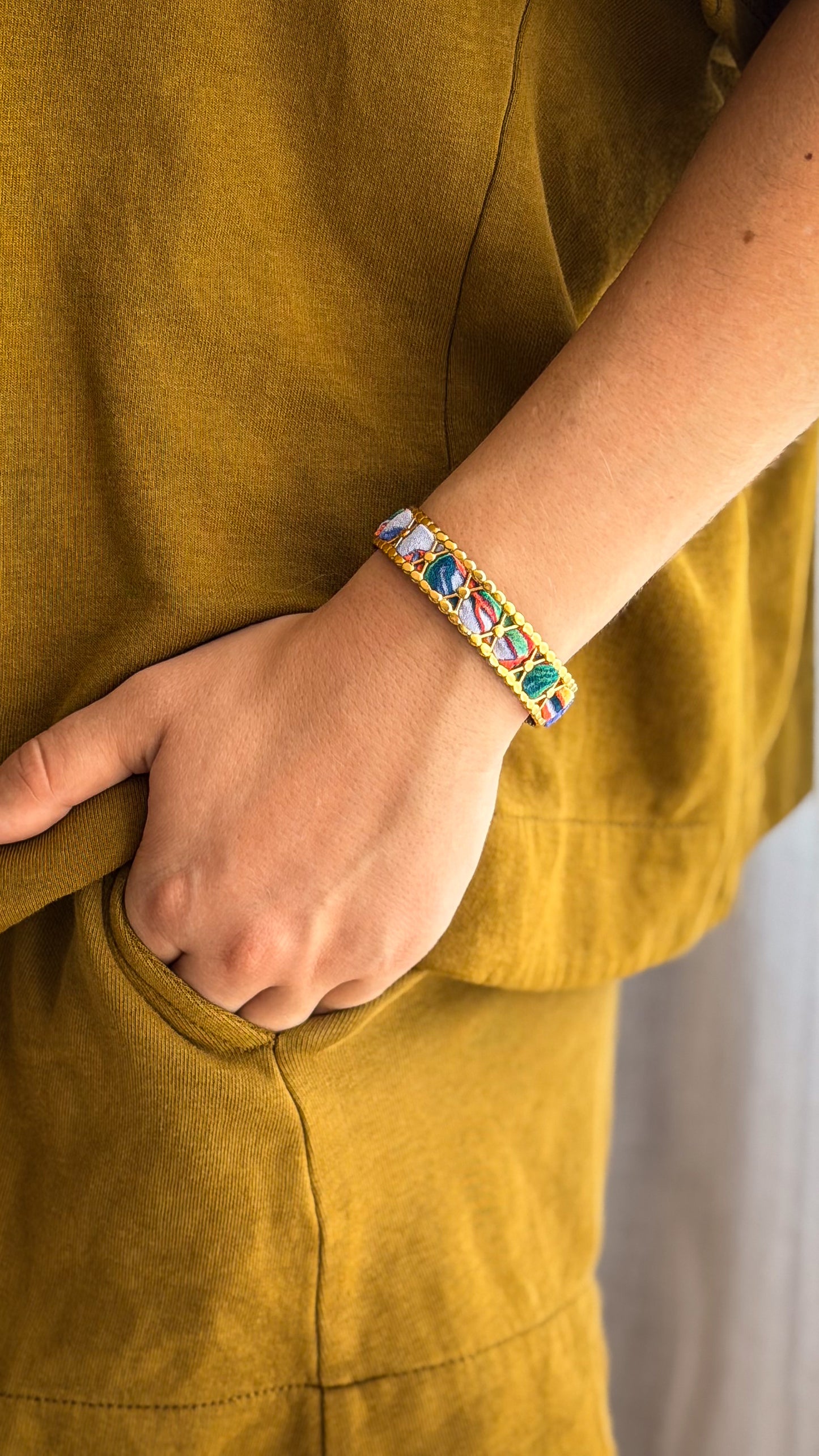 Bracelet jonc en acier inoxydable et tissu upcyclé motif fleurs bleu et corail, porté au poignet