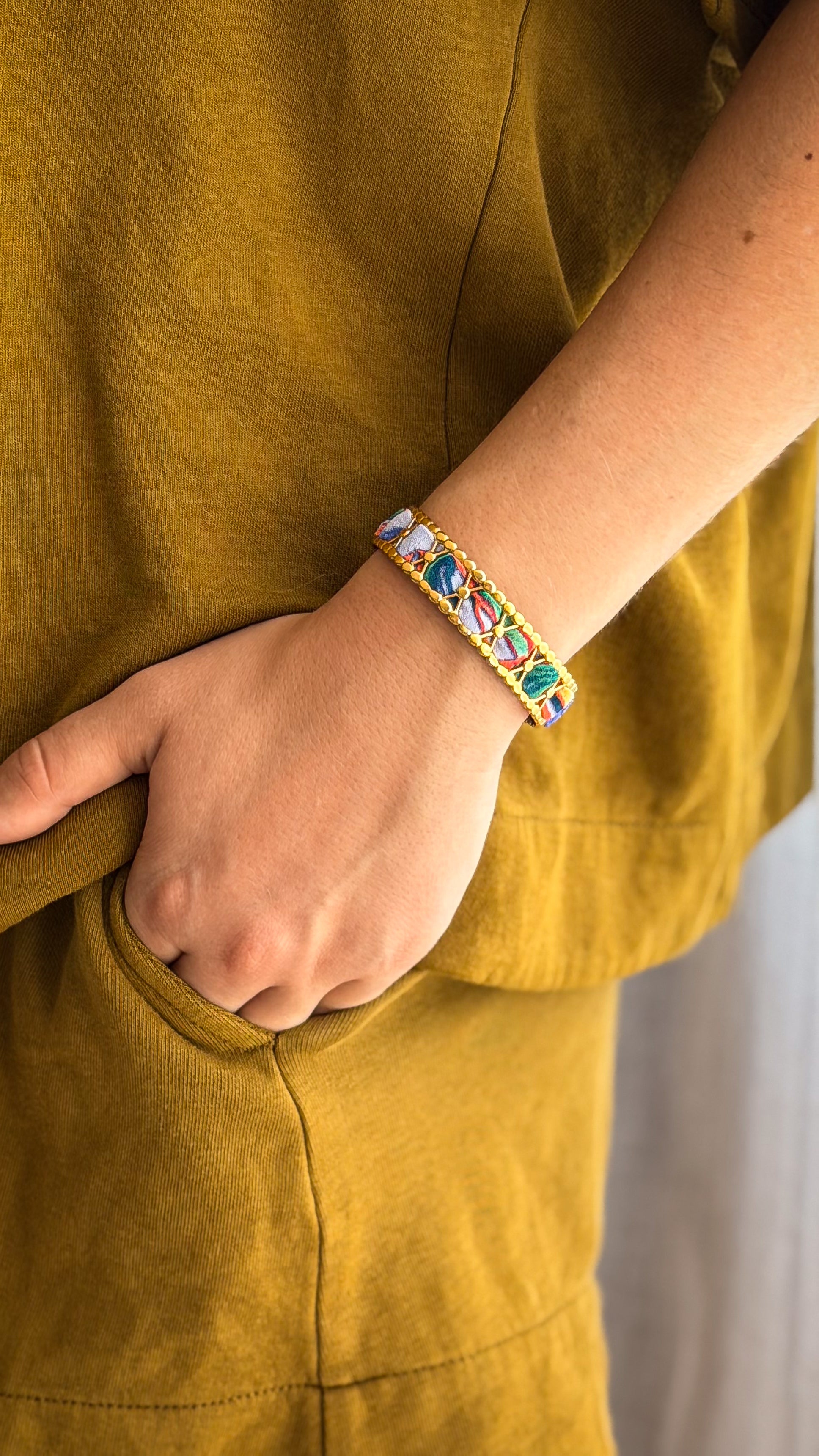 Bracelet jonc en acier inoxydable et tissu upcyclé motif fleurs bleu et corail, porté au poignet