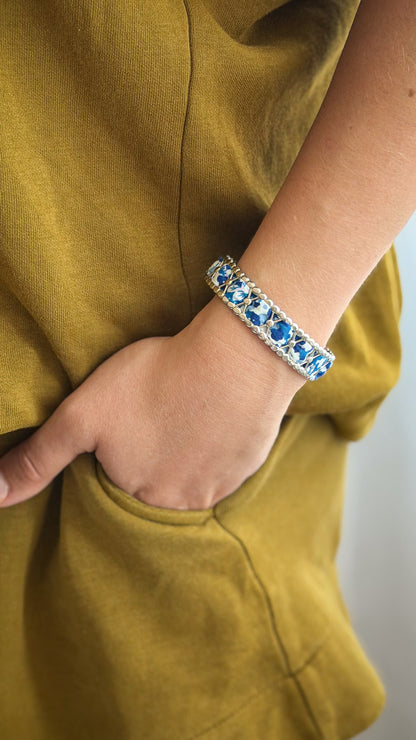Bracelet jonc en acier inoxydable et tissu upcyclé argenté motif fleurs bleues, porté au poignet