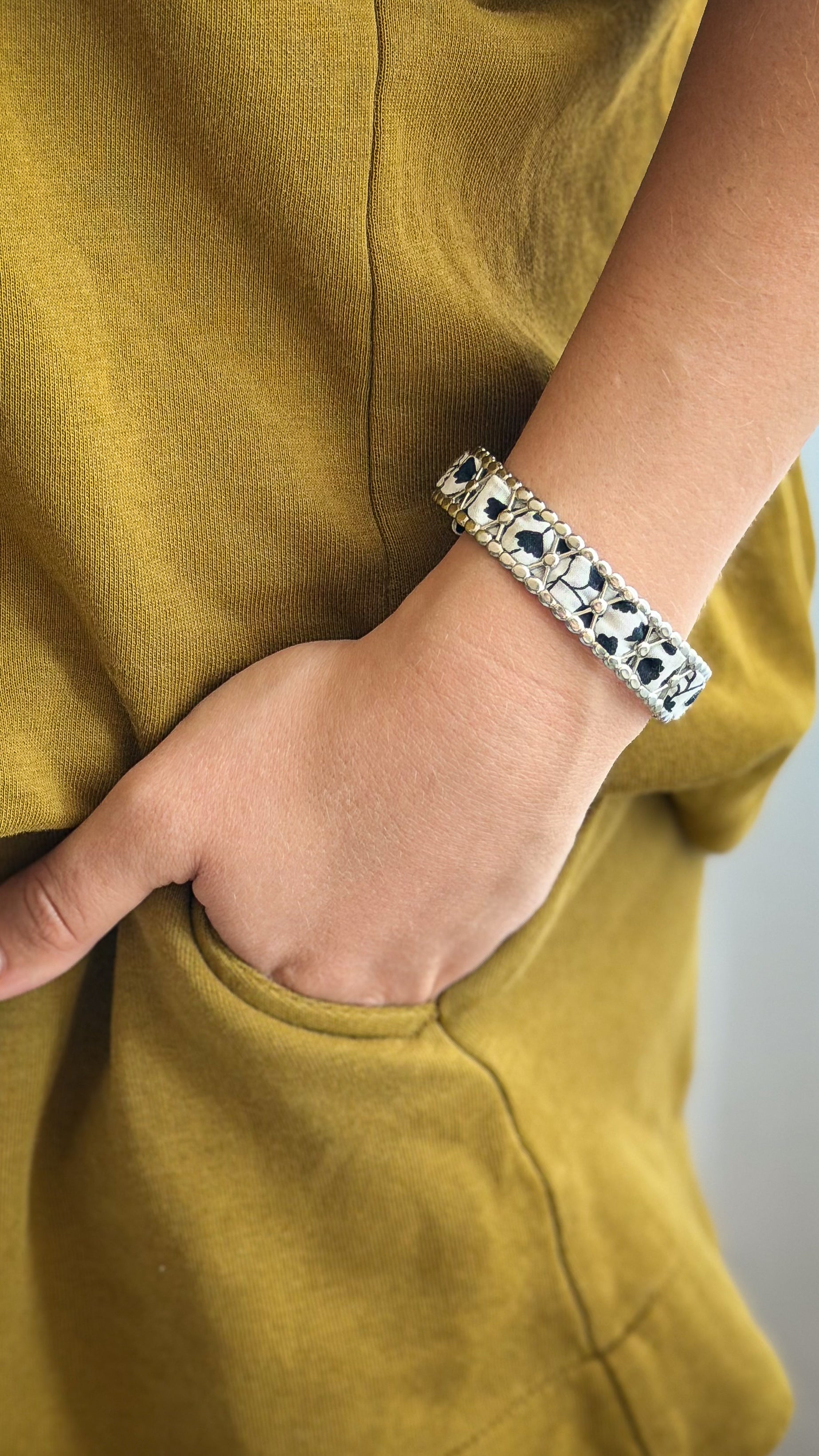 Bracelet jonc en acier inoxydable et tissu upcyclé argenté motif fleurs noir et blanc, porté au poignet