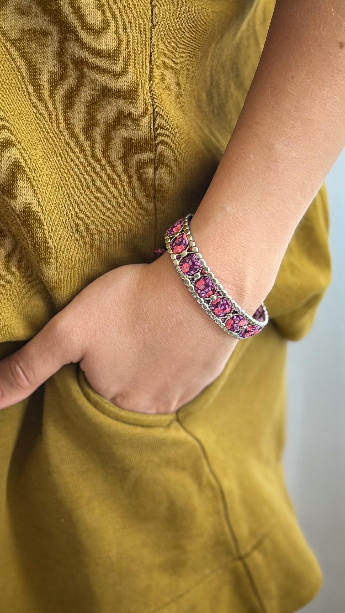 Bracelet jonc en acier inoxydable et tissu upcyclé argenté motif fleurs prune, porté au poignet