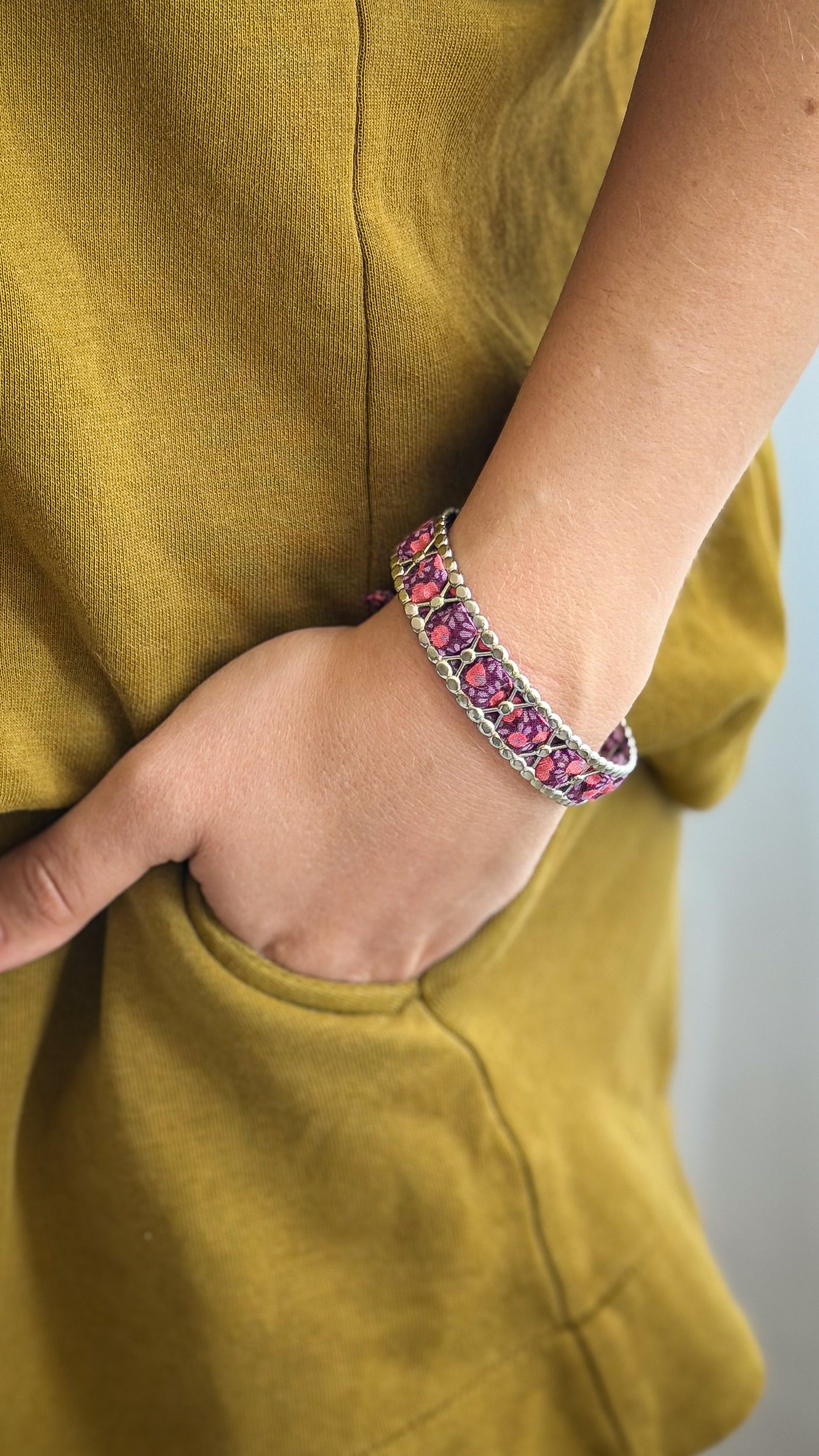 Bracelet jonc en acier inoxydable et tissu upcyclé argenté motif fleurs prune, porté au poignet