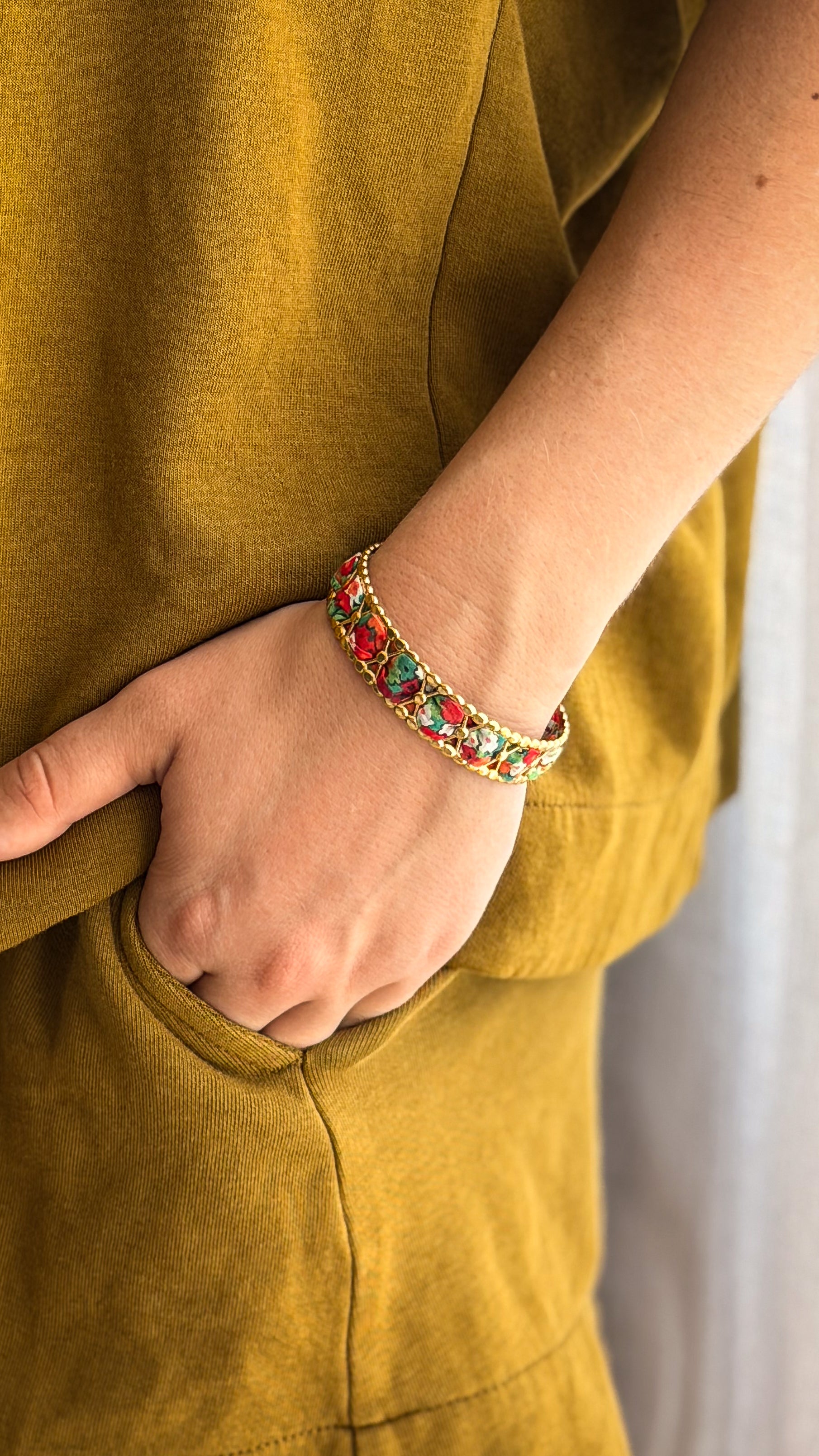 Bracelet jonc en acier inoxydable et tissu upcyclé motif fleurs rouges, porté au poignet