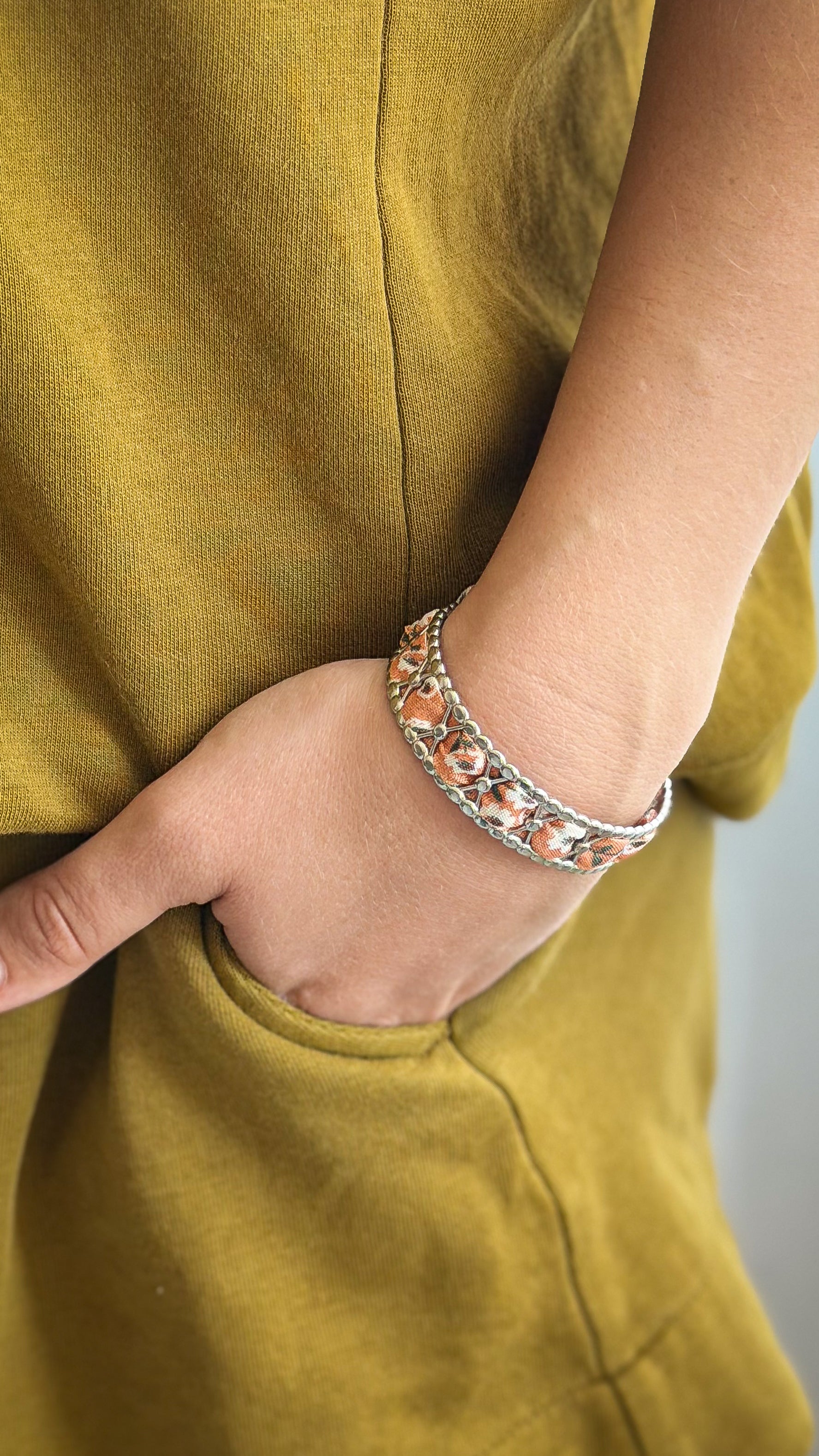 Bracelet jonc en acier inoxydable et tissu upcyclé argenté motif fleurs terracotta, porté au poignet