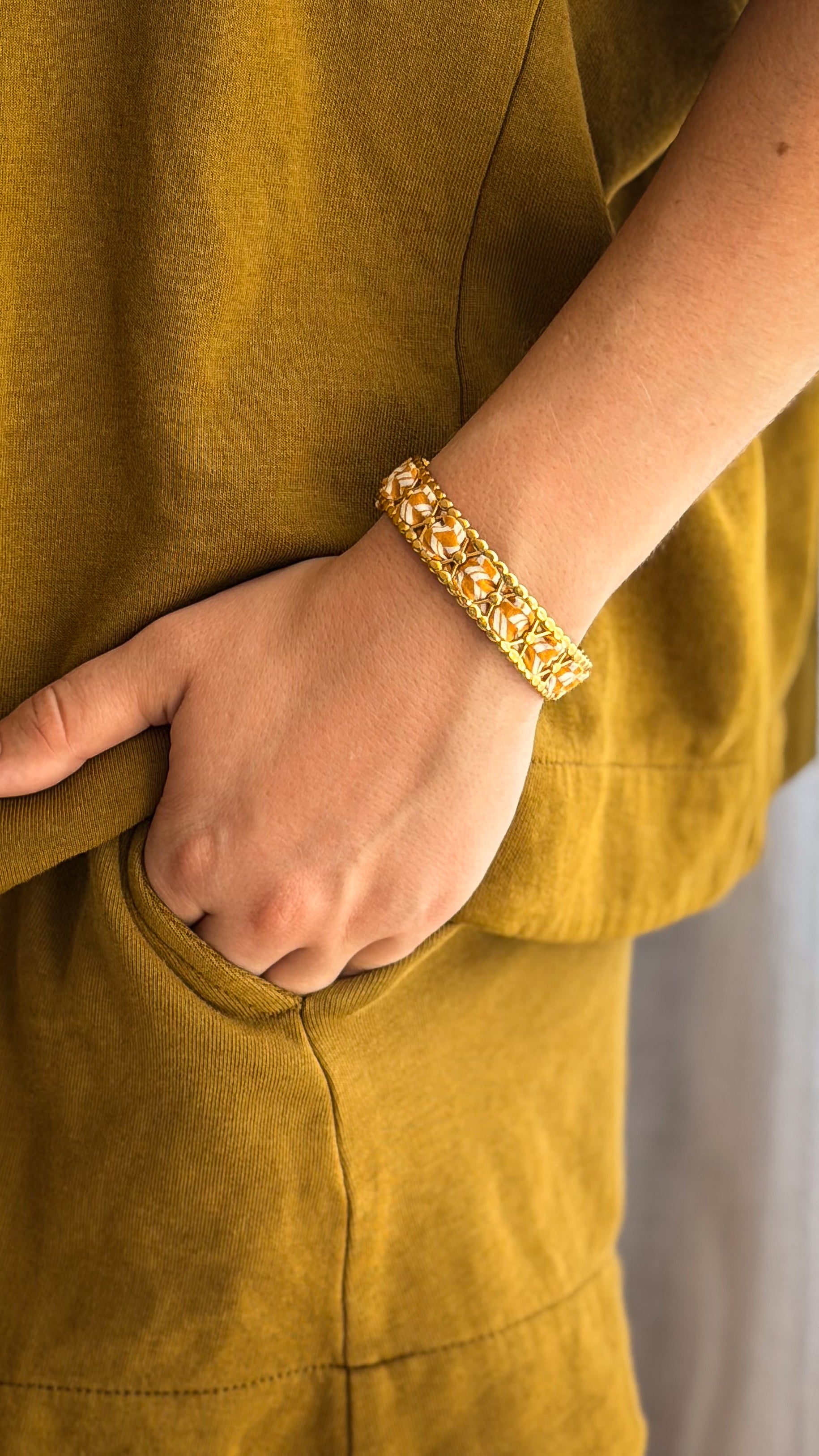 Bracelet jonc en acier inoxydable et tissu upcyclé motif moutarde et blanc, porté au poignet